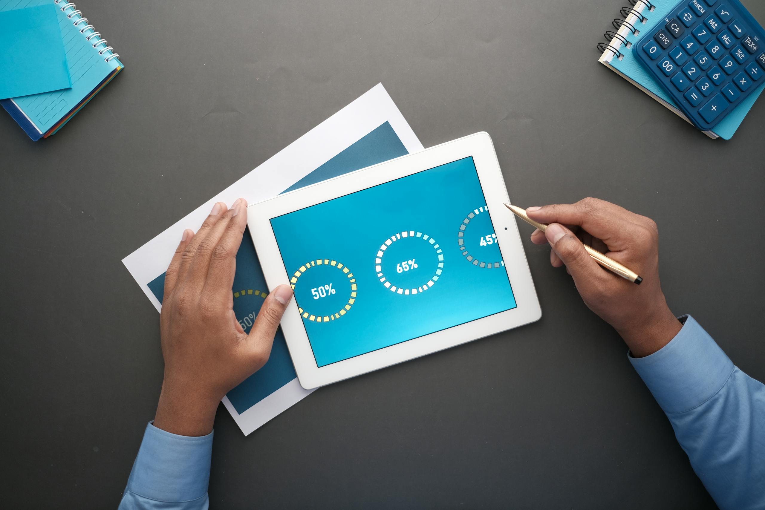 A professional reviewing statistical data on a digital tablet. Top view of business analysis.