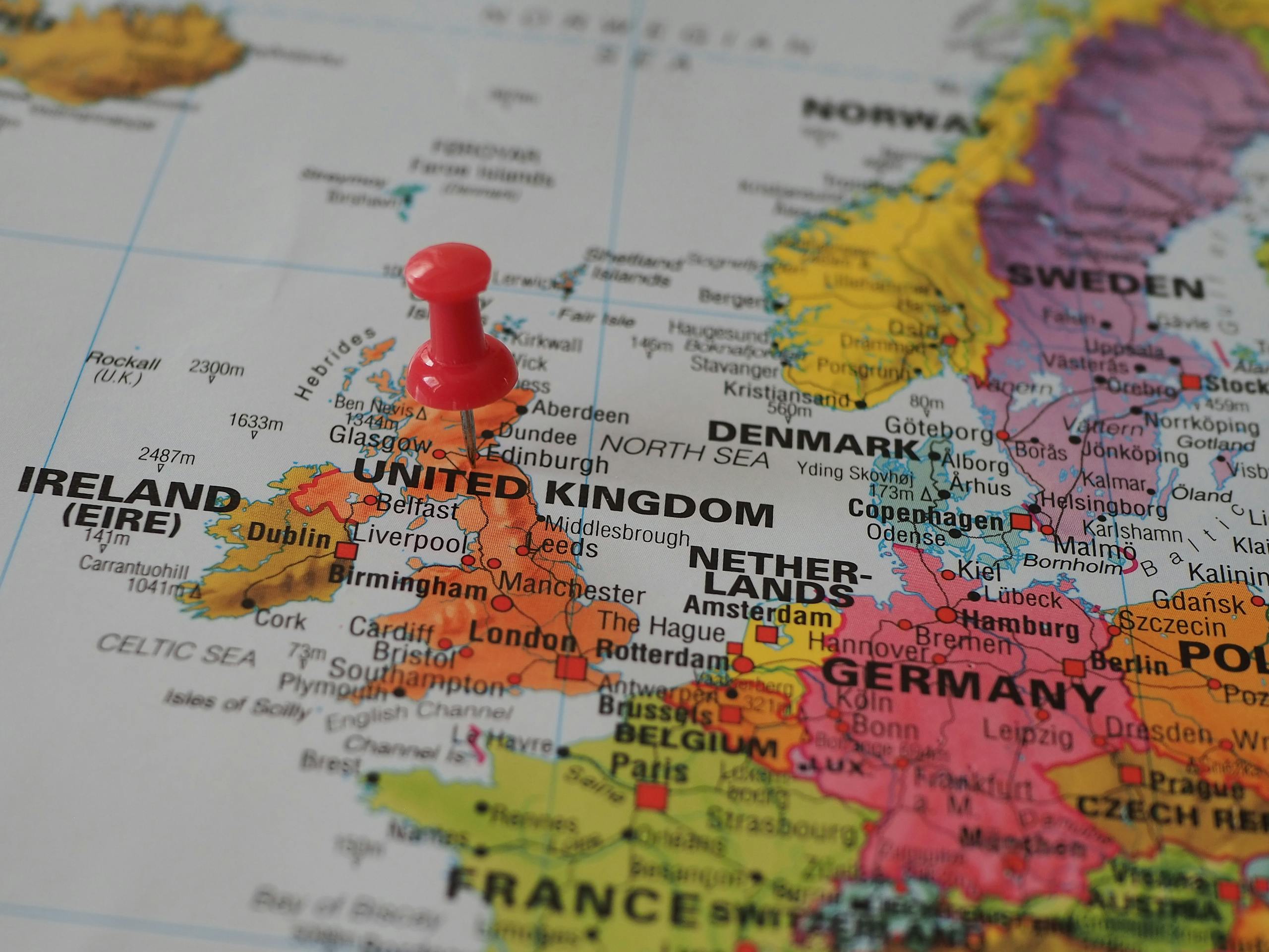 Close-up of a European map highlighting the UK with a red pin, perfect for geography themes.