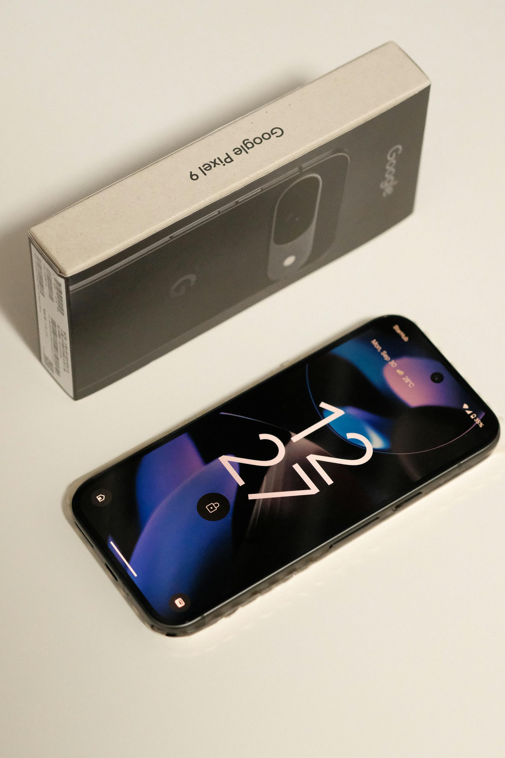 Close-up of Google Pixel 9 smartphone with the original packaging box, showcasing sleek design.