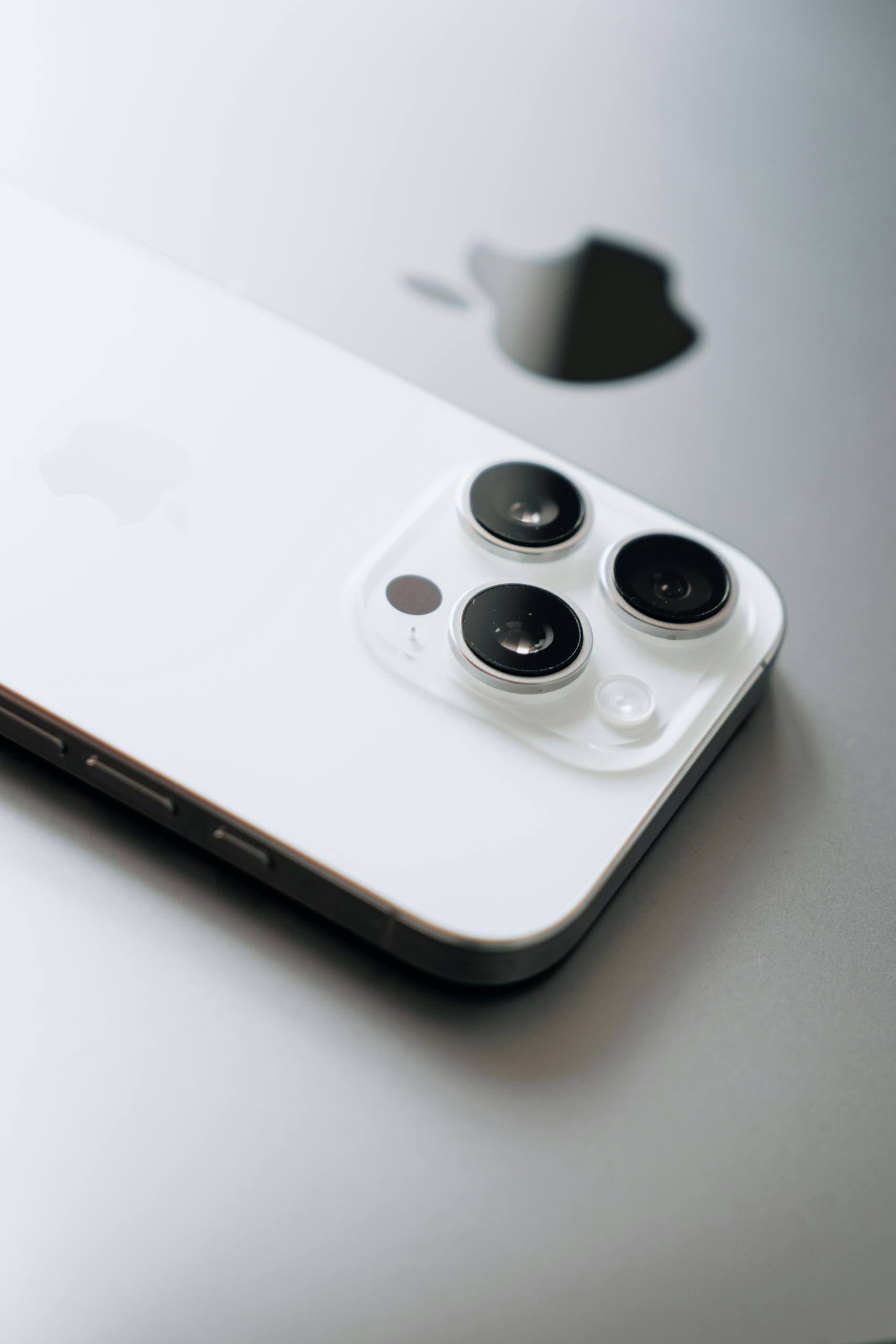 White smartphone with triple cameras lies atop a sleek laptop.